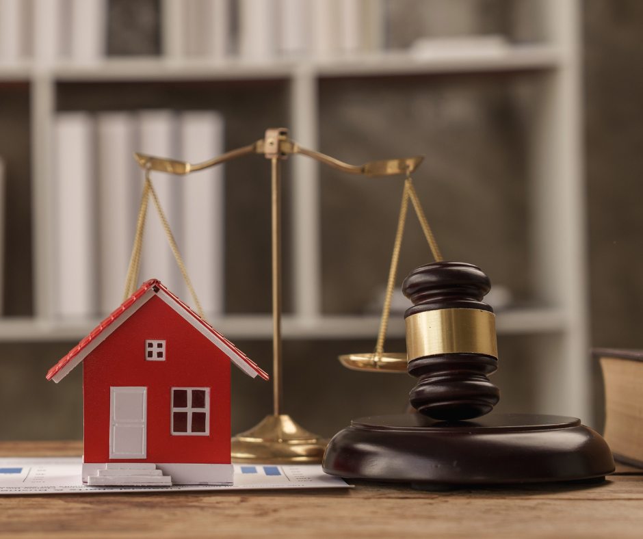A red house figure, gold scale balance, and a gavel on a table
